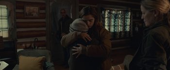 Movie still from “The Silence” (2019), directed by John R. Leonetti – Two people hugging each other in a living room; Medium shot, Over the shoulder angle