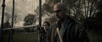 Movie still from “The Silence” (2019), directed by John R. Leonetti – A man and a woman standing next to each other in front of a wire fence; Close Up shot, Over the shoulder angle