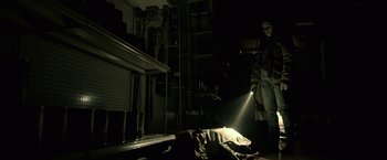 Movie still from “The Silence” (2019), directed by John R. Leonetti – A man standing next to a bed in the dark; Wide shot, Low angle