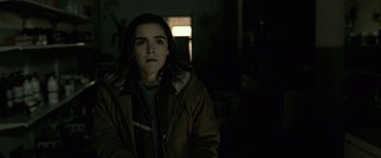 Movie still from “The Silence” (2019), directed by John R. Leonetti – A woman is standing in a dark room; Medium shot, Over the shoulder angle