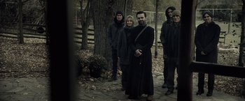 Movie still from “The Silence” (2019), directed by John R. Leonetti – A group of people standing next to a tree; Medium shot, Low angle