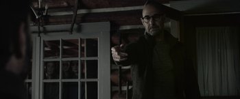Movie still from “The Silence” (2019), directed by John R. Leonetti – A man with glasses is pointing at the camera; Medium shot, Over the shoulder angle