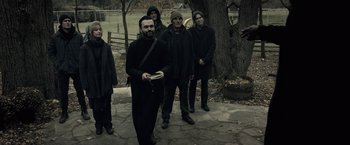 Movie still from “The Silence” (2019), directed by John R. Leonetti – A group of people standing next to a tree; Medium shot, Low angle