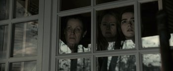 Movie still from “The Silence” (2019), directed by John R. Leonetti – Two women and a man looking out of a window; Medium shot, Low angle