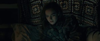 Movie still from “The Silence” (2019), directed by John R. Leonetti – A woman is laying down on a bed looking at her cell phone; Medium shot, High angle