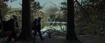 Movie still from “The Silence” (2019), directed by John R. Leonetti – A man walking on a path near a body of water; Extreme Wide shot, Low angle