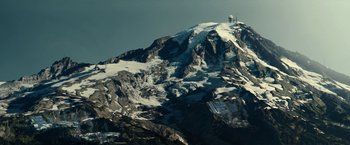 Movie still from “The Silence” (2019), directed by John R. Leonetti – A large mountain with snow on top of it; Extreme Wide shot, High angle