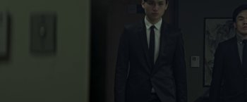 Movie still from “The Soul” (2021), directed by Wei-Hao Cheng – A man wearing a suit and tie standing in a room; Medium shot, Low angle
