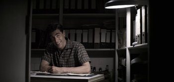 Movie still from “The Spy” (2019), directed by Gideon Raff – A man sitting at a desk in front of papers; Medium shot, Over the shoulder angle