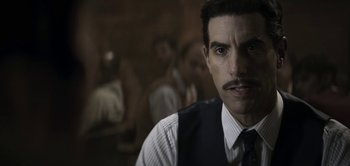 Movie still from “The Spy” (2019), directed by Gideon Raff – A person wearing a vest and a tie; Close Up shot, Over the shoulder angle