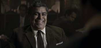 Movie still from “The Spy” (2019), directed by Gideon Raff – A person wearing a suit and tie; Close Up shot, Over the shoulder angle