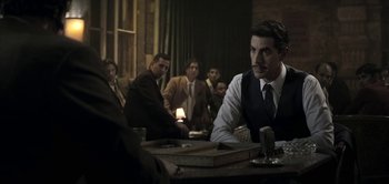Movie still from “The Spy” (2019), directed by Gideon Raff – A group of men sitting at a table in a room; Medium shot, Over the shoulder angle