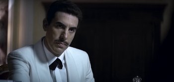 Movie still from “The Spy” (2019), directed by Gideon Raff – A man in a white suit and a black tie; Close Up shot, Low angle
