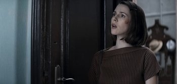 Movie still from “The Spy” (2019), directed by Gideon Raff – A woman standing in front of a wooden door; Close Up shot, Over the shoulder angle