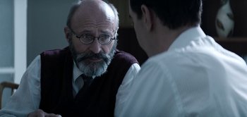 Movie still from “The Spy” (2019), directed by Gideon Raff – An older man wearing glasses talking to a younger man; Close Up shot, Over the shoulder angle