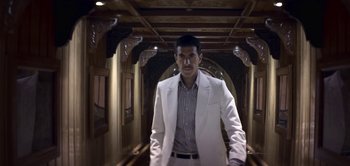 Movie still from “The Spy” (2019), directed by Gideon Raff – A man in a white suit standing in a hallway; Medium shot, Low angle