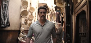 Movie still from “The Spy” (2019), directed by Gideon Raff – A man standing in front of a market stall; Medium shot, Over the shoulder angle