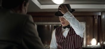 Movie still from “The Spy” (2019), directed by Gideon Raff – A man in a hat and a vest looking at another man in a suit and bow tie; Close Up shot, Low angle