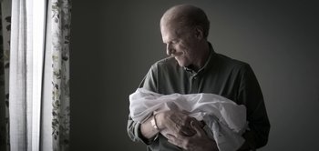 Movie still from “The Spy” (2019), directed by Gideon Raff – An older man holding a baby in his arms; Close Up shot, High angle
