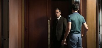 Movie still from “The Spy” (2019), directed by Gideon Raff – A man standing in front of another man in front of a door; Medium shot, Over the shoulder angle