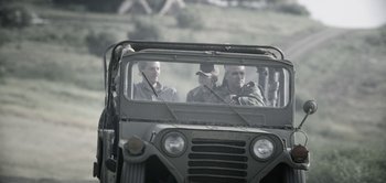 Movie still from “The Spy” (2019), directed by Gideon Raff – Two men are in the back of an army vehicle; Wide shot, Over the shoulder angle