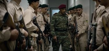 Movie still from “The Spy” (2019), directed by Gideon Raff – A group of men standing next to each other holding guns; Wide shot, Low angle