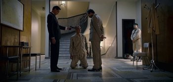 Movie still from “The Spy” (2019), directed by Gideon Raff – Three men in suits and ties standing in front of a staircase; Wide shot, High angle