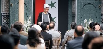 Movie still from “The Spy” (2019), directed by Gideon Raff – A man in a white hat is talking to a group of people; Wide shot, Over the shoulder angle