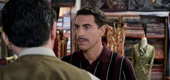 Movie still from “The Spy” (2019), directed by Gideon Raff – A man with a mustache talking to another man in a store; Close Up shot, Over the shoulder angle