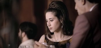 Movie still from “The Spy” (2019), directed by Gideon Raff – A young woman sitting at a table with a glass; Close Up shot, Over the shoulder angle