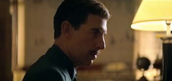 Movie still from “The Spy” (2019), directed by Gideon Raff – A person wearing a suit and tie; Close Up shot, Over the shoulder angle