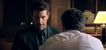 Movie still from “The Spy” (2019), directed by Gideon Raff – A man wearing a suit and tie talking to another man in front of him; Close Up shot, Over the shoulder angle