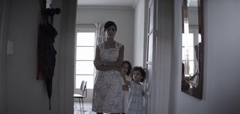 Movie still from “The Spy” (2019), directed by Gideon Raff – A woman and two girls standing in front of a door; Medium shot, Low angle