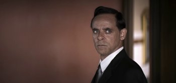 Movie still from “The Spy” (2019), directed by Gideon Raff – A person wearing a suit and tie; Close Up shot, Over the shoulder angle