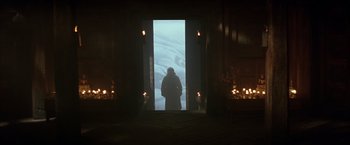 Movie still from “Batman Begins” (2005), directed by Christopher Nolan – A man standing in front of a large open door; Wide shot, Low angle