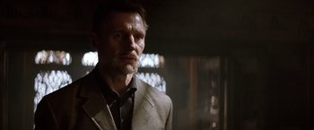 Movie still from “Batman Begins” (2005), directed by Christopher Nolan – A person wearing a suit and tie; Close Up shot, Low angle