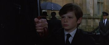 Movie still from “Batman Begins” (2005), directed by Christopher Nolan – A boy in a suit holding an umbrella in the rain; Close Up shot, Low angle