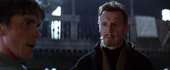 Movie still from “Batman Begins” (2005), directed by Christopher Nolan – Liam neeson wearing a black jacket; Close Up shot, Low angle