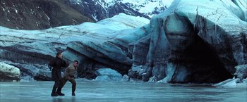 Movie still from “Batman Begins” (2005), directed by Christopher Nolan – A man standing on a frozen lake in front of a mountain range; Extreme Wide shot, Low angle