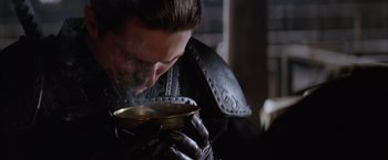 Movie still from “Batman Begins” (2005), directed by Christopher Nolan – A man in a leather jacket drinking from a brass cup; Close Up shot, Low angle