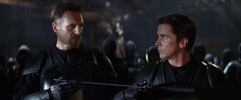 Movie still from “Batman Begins” (2005), directed by Christopher Nolan – Two men in black leather jackets are looking at each other; Close Up shot, Over the shoulder angle
