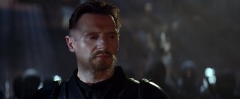 Movie still from “Batman Begins” (2005), directed by Christopher Nolan – A person with a beard; Close Up shot, Over the shoulder angle