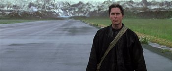 Movie still from “Batman Begins” (2005), directed by Christopher Nolan – A man standing in front of a body of water; Medium shot, Low angle
