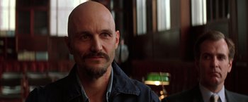 Movie still from “Batman Begins” (2005), directed by Christopher Nolan – A bald man with a beard and a mustache; Close Up shot, Low angle