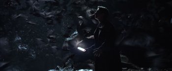 Movie still from “Batman Begins” (2005), directed by Christopher Nolan – A man holding a flashlight while standing next to a flock of birds; Medium shot, High angle