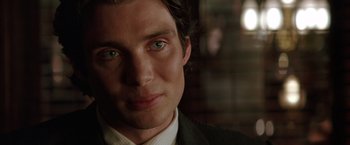 Movie still from “Batman Begins” (2005), directed by Christopher Nolan – A person wearing a suit and tie; Close Up shot, Over the shoulder angle