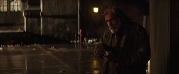 Movie still from “Batman Begins” (2005), directed by Christopher Nolan – An old man standing on the side of the road holding a remote control; Medium shot, Over the shoulder angle