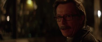 Movie still from “Batman Begins” (2005), directed by Christopher Nolan – A person wearing glasses and a beard; Close Up shot, Over the shoulder angle