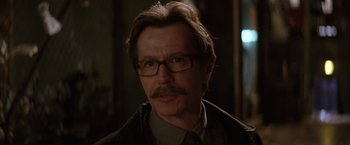 Movie still from “Batman Begins” (2005), directed by Christopher Nolan – A person wearing glasses and a tie; Close Up shot, Over the shoulder angle