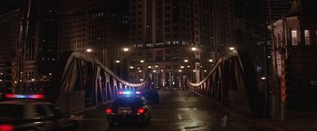 Movie still from “Batman Begins” (2005), directed by Christopher Nolan – Two police cars driving on a bridge at night; Extreme Wide shot, High angle